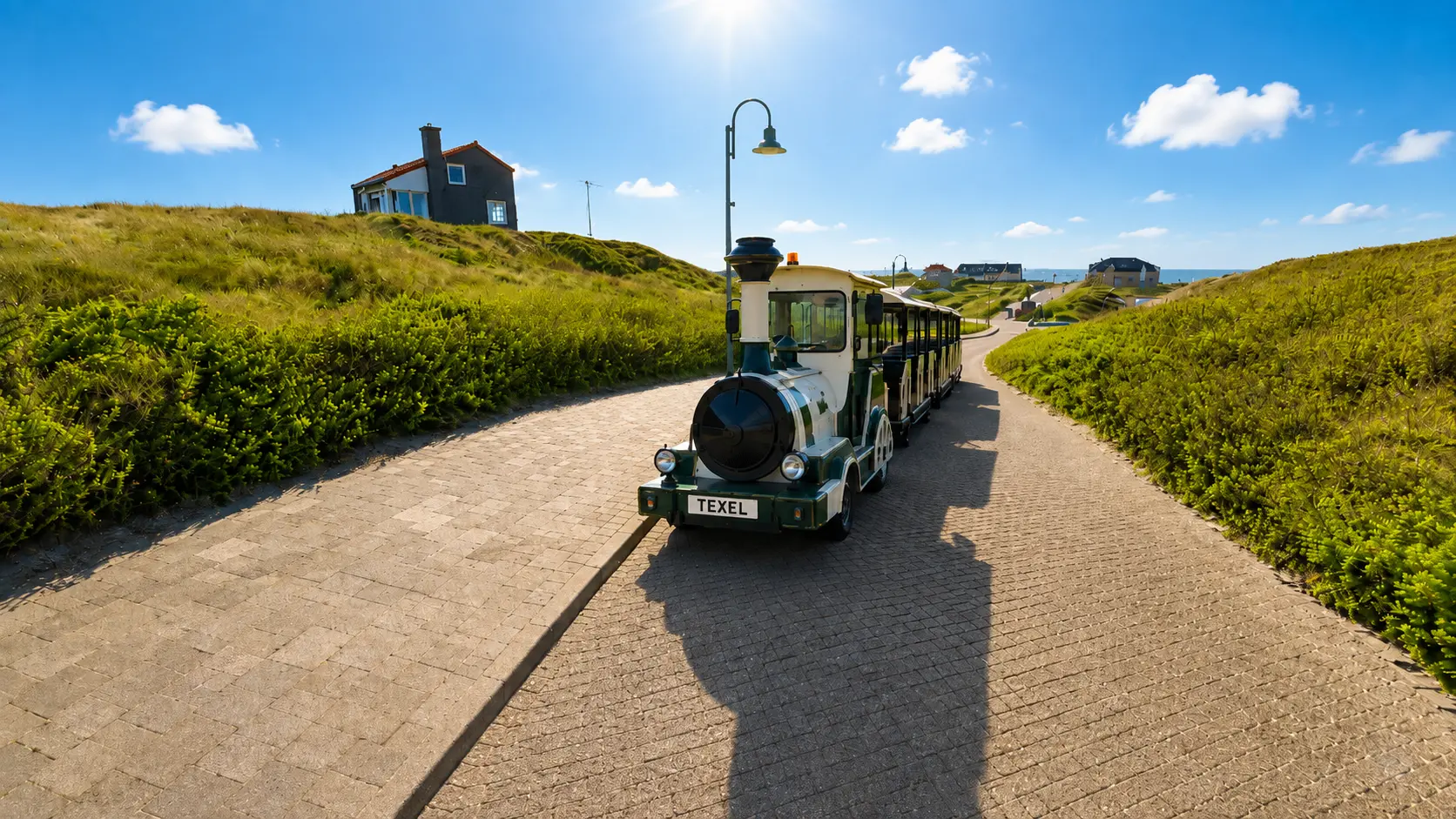 Het treintje op de Badweg tussen de duinen, met de zee in de verte.